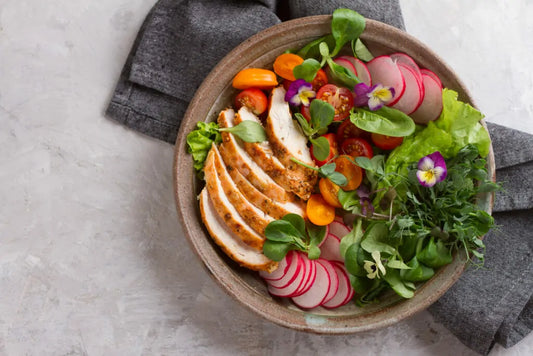 Salad bowl with vegetables, chicken and edible flowers